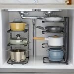 A multi-layer stainless steel pot rack organizer standing on a kitchen counter, holding various pots and pans neatly.