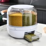 A white 6-grid rotating food dispenser on a kitchen counter, with different grains like rice and beans visible in each compartment.